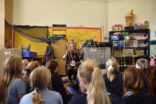 Artist demoing how to make a willow lantern structure in front of class of school children