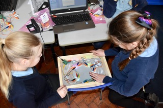 2 girls attaching wires and technology and lights to their art lightbox
