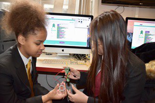 2 girls working with Codebug device in front of a computer