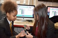 2 girls working with Codebug device in front of a computer